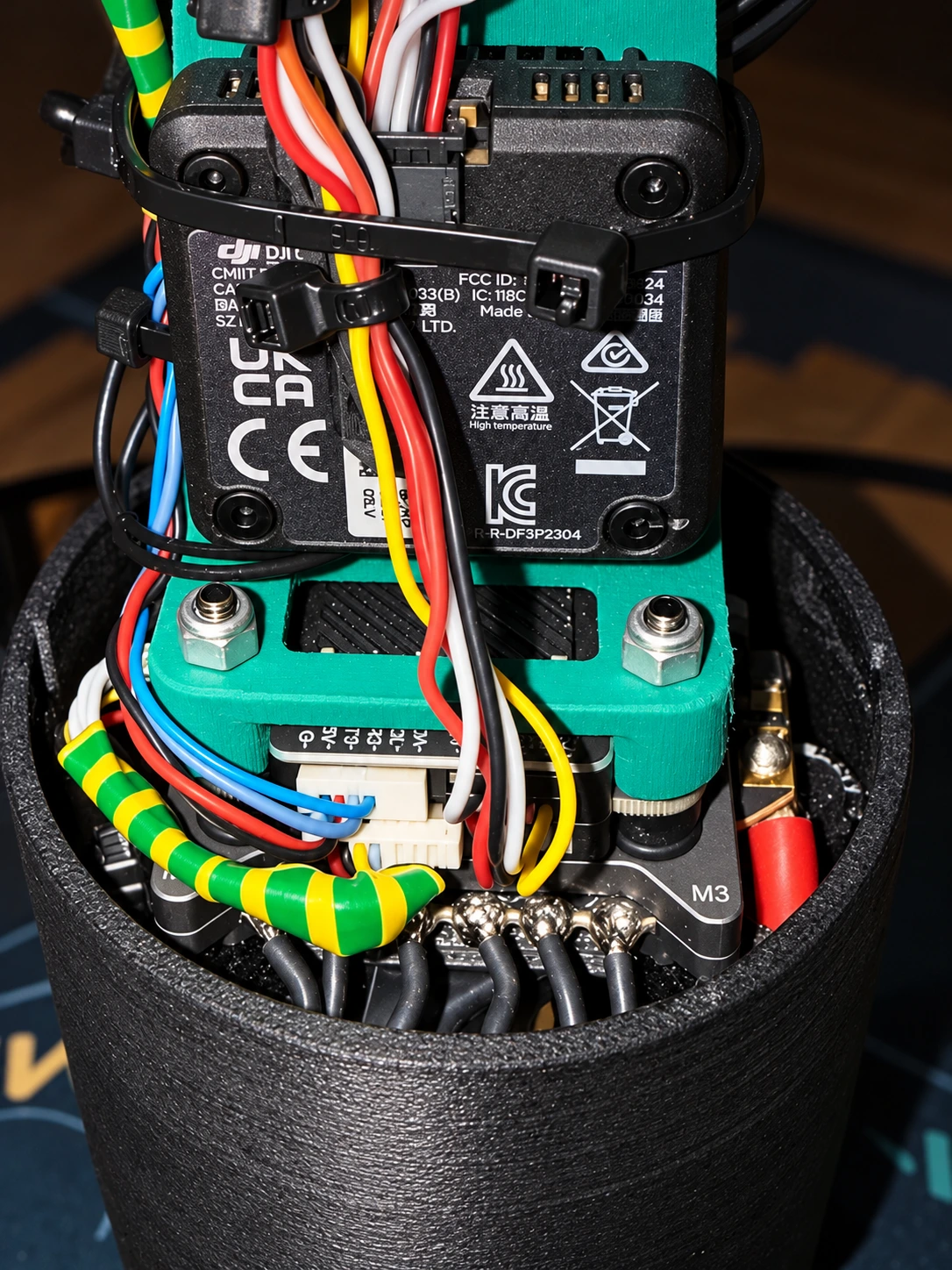 Interiorul fuselajului negru cu electronică verde, module și cabluri colorate fixate cu coliere